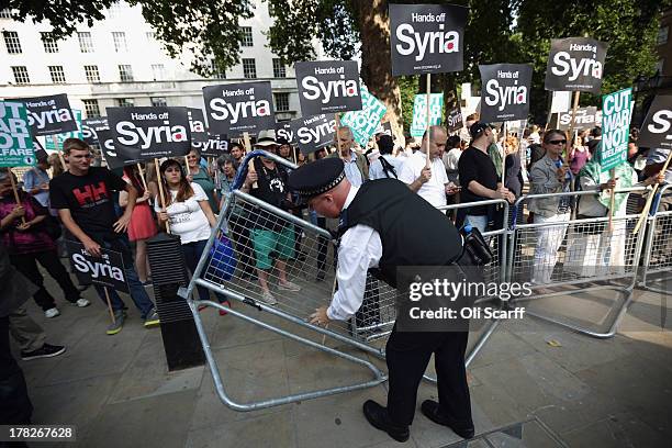 Police officer lays out crowd control barriers as protesters gather on Whitehall outside Downing Street to campaign for no international military...