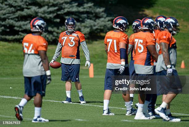 Denver Broncos guard Chris Kuper prepare to throw passes to the offensive line during drills at practice August 28, 2013 at Dove Valley.