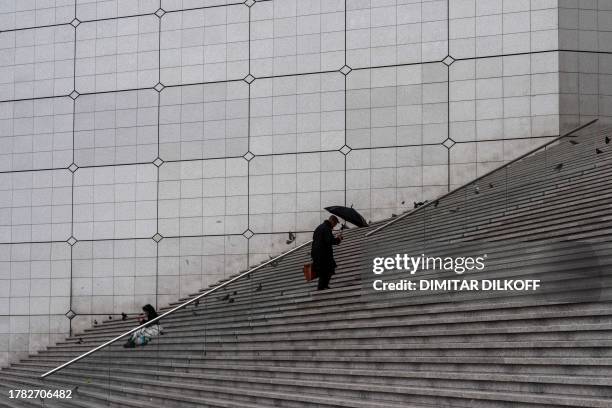 Man climbs the stairs of "La Grande Arche de la Defense" at the financial and business district of La Defense near Paris on November 14, 2023.