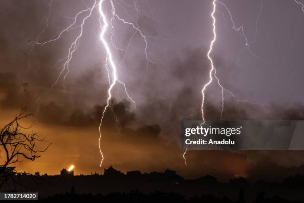 View of lightning illuminating the sky accompanied by rising smoke, aftermath of Israeli attacks, is captured as air raids subside over Gaza amidst...