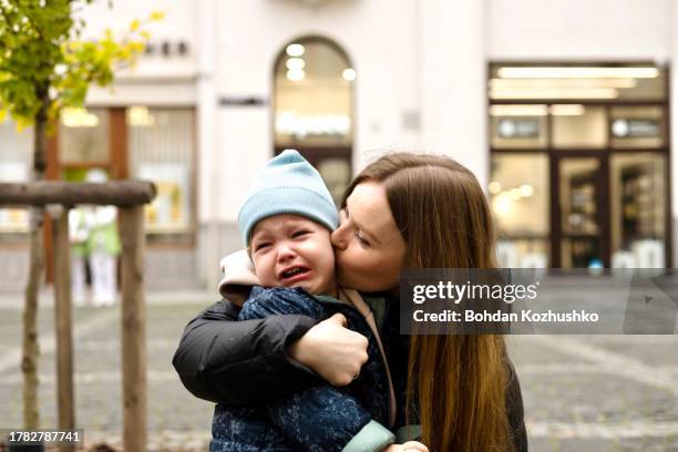 a little boy cries in his mother's arms, as she consoles him - cleaning equipment stock pictures, royalty-free photos & images