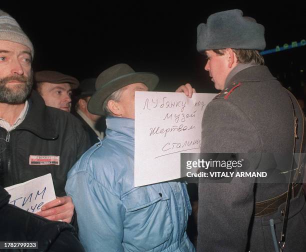 Man holds up a poster that reads "We should turn Lubianka into a Museum of Stalinism" as he faces a Soviet militiaman during a rally called by...
