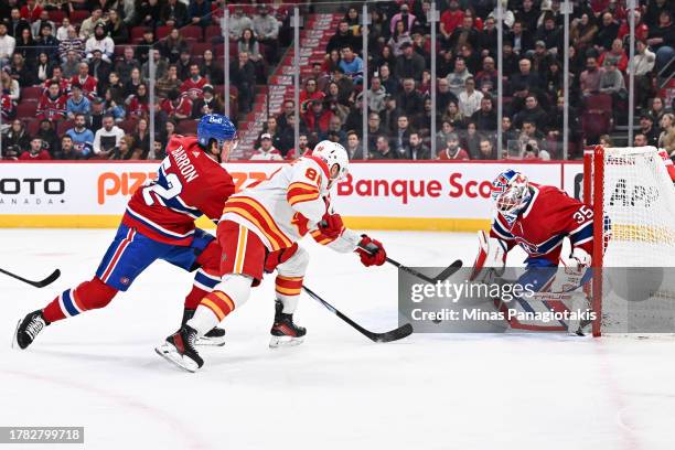 Justin Barron and goaltender Sam Montembeault of the Montreal Canadiens defend against Andrew Mangiapane of the Calgary Flames in the first period at...