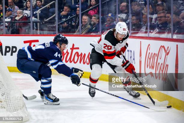 Michael McLeod of the New Jersey Devils plays the puck along the boards as Josh Morrissey of the Winnipeg Jets defends during first period action at...