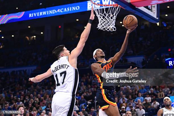 Shai Gilgeous-Alexander of the Oklahoma City Thunder goes up for a layup while being defended by Doug McDermott of the San Antonio Spurs during the...
