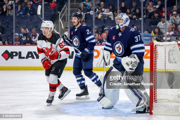 Jesper Bratt of the New Jersey Devils, Mason Appleton and goaltender Connor Hellebuyck of the Winnipeg Jets keep an eye on the play during first...