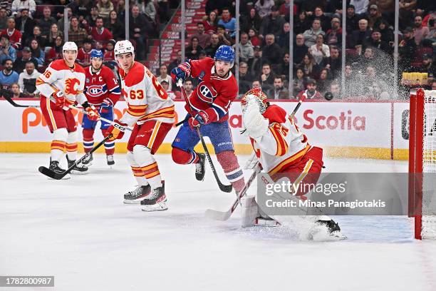 Alex Newhook of the Montreal Canadiens skates near goaltender Jacob Markstrom of the Calgary Flames as the puck passes them during the second period...