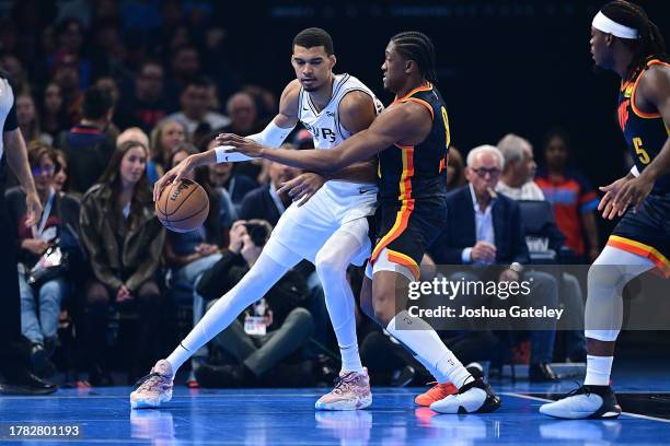 Victor Wembanyama of the San Antonio Spurs handles the ball while being defended by Jalen Williams of the Oklahoma City Thunder during the first half...