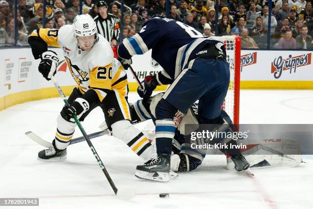 Elvis Merzlikins of the Columbus Blue Jackets and Kirill Marchenko attempt to check Lars Eller of the Pittsburgh Penguins away from a loose puck...