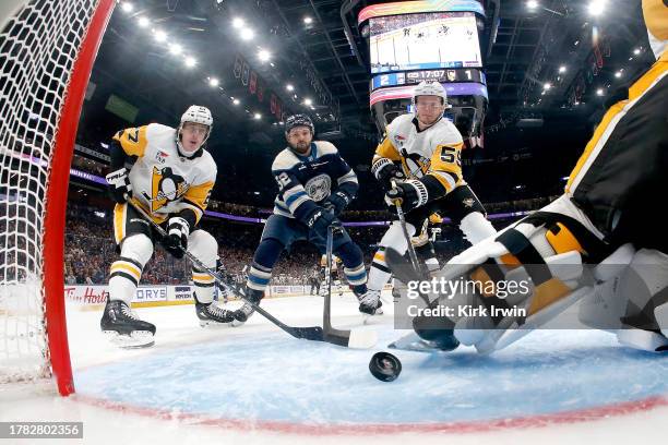 Jake Guentzel of the Pittsburgh Penguins and Ryan Graves attempt to clear out the puck away from Emil Bemstrom of the Columbus Blue Jackets during...