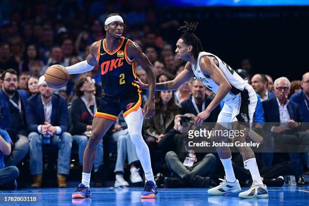 Shai Gilgeous-Alexander of the Oklahoma City Thunder handles the ball while being defended by Devin Vessell of the San Antonio Spurs during the...