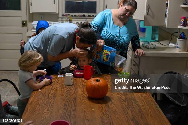 Issabella Edmisten eats a bowl of cereal as Karen Edminsten kisses the head of her grandson Jayne Edminsten and Sierra Edmisten pours cereal into a...