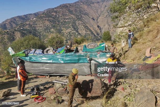 Police personnel attends a phone call near the wrecked bus, subject to an accident on a remote mountain road in the Doda area, about 200 kilometres...