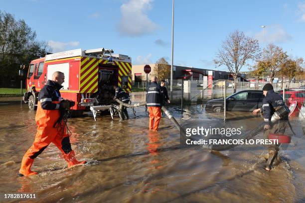 Firefighters operate, preparing to pump water in a flooded area next to a car store in Saint-Leonard, northern France on November 15, 2023. After two...