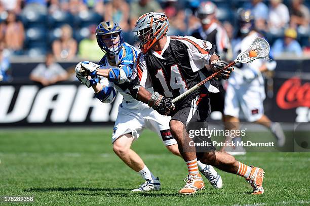 Justin Pennington of the Denver Outlaws runs past Casey Cittadino of the Charlotte Hounds during the 2013 MLL Semifinal game at PPL Park on August...