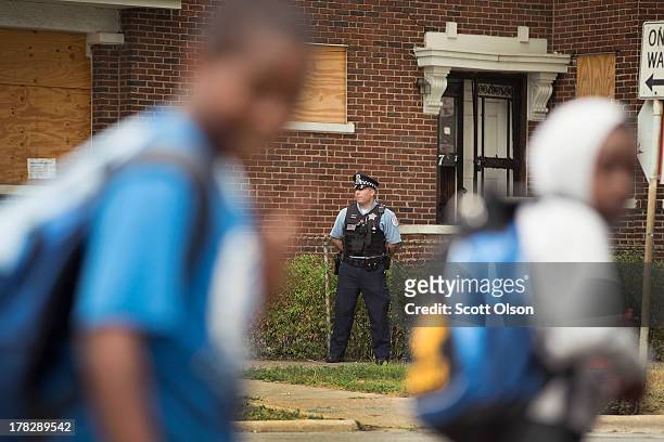 Chicago Police Officer John Bertetto stands outside a boarded-up home while he watches students walk home from Laura Ward Elementary school on the...