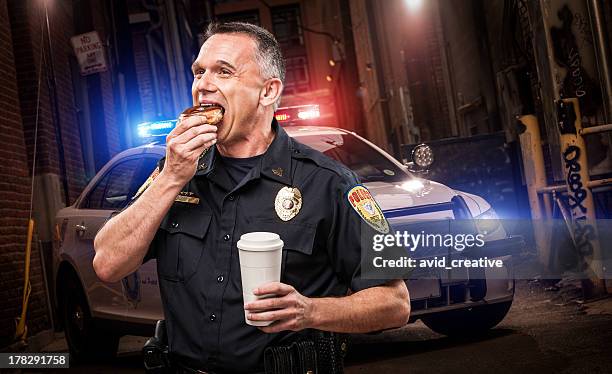 police officer eating donut in alley - donut man stock pictures, royalty-free photos & images