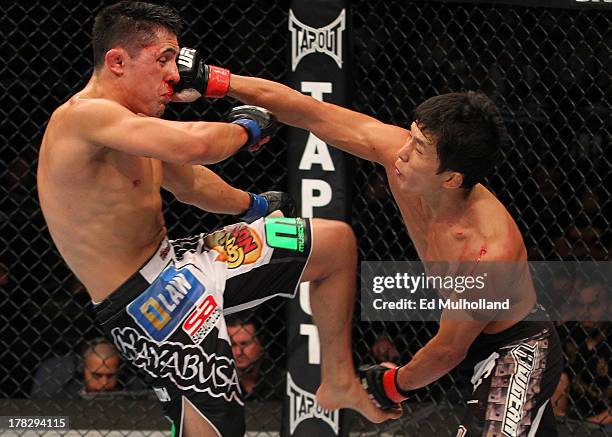 Takeya Mizugaki punches Erik Perez in their bantamweight fight during the UFC on FOX Sports 1 event at Bankers Life Fieldhouse on August 28, 2013 in...