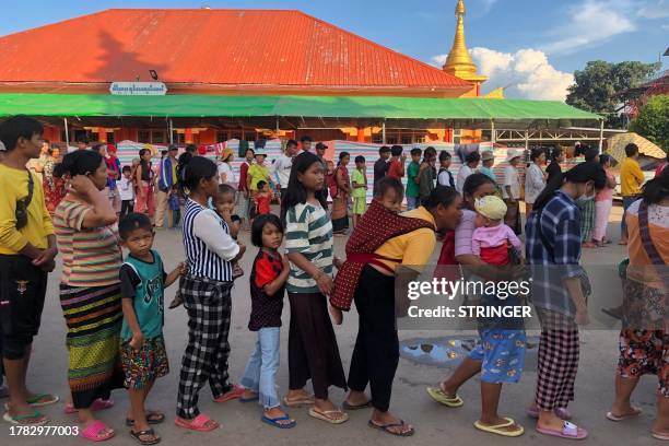 People queue for food at a monastery-turned-temporary shelter for internally displaced people in Lashio, Shan state on November 15, 2023. Fighting...