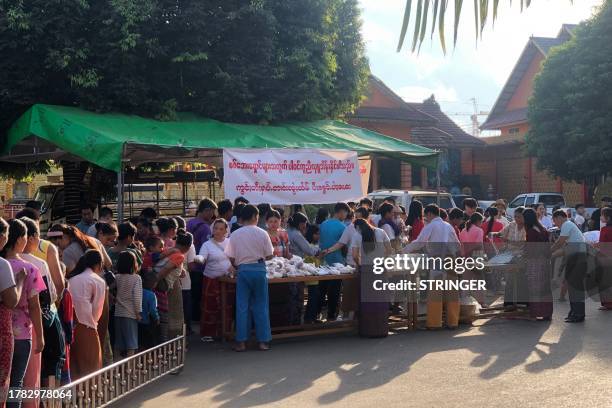 People queue for food at a monastery-turned-temporary shelter for internally displaced people in Lashio, Shan state on November 15, 2023. Fighting...