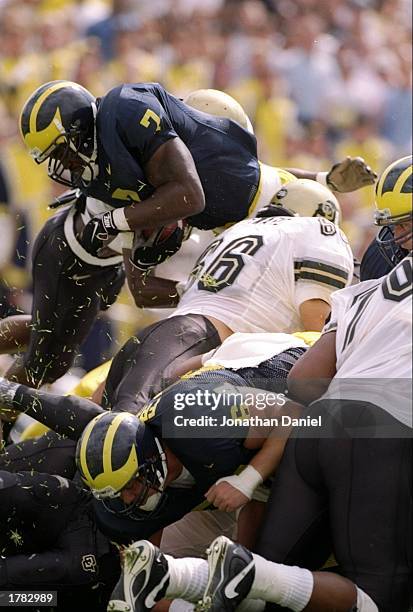 Fullback Chris Floyd of the Michigan Wolverines is aided by teammate and center Steve Frazier in scoring a touchdown as linebacker Brandon Southward...