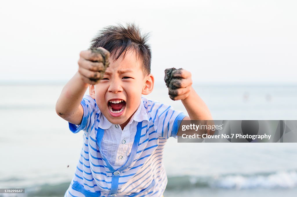 Little boy playing with sand on the beach.