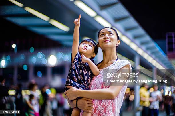 young mom holding toddler on street at night - tochter zeigt stock-fotos und bilder