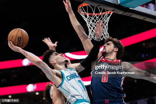 LaMelo Ball of the Charlotte Hornets drives to the basket while guarded by Deni Avdija of the Washington Wizards in the fourth quarter during their...