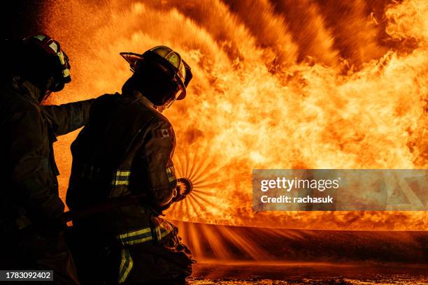 firefighters operating a water fire car - capacete de bombeiro imagens e fotografias de stock