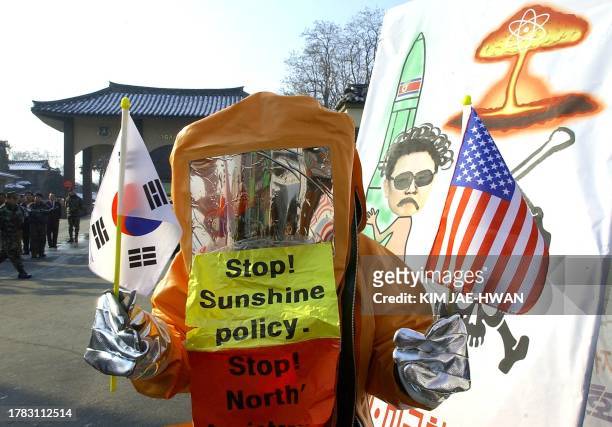 South Korean demonstrator wave US and South Korean flags in front of a poster displaying North Korean leader Kim Jong-Il riding a nuclear missile 08...