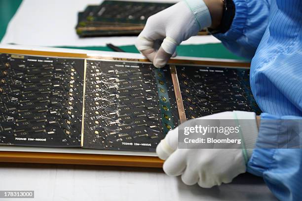 An employee attaches protective film to a Flexible Printed Circuit Board panel on the production line at the Seil Electronics Co. Factory in Incheon,...