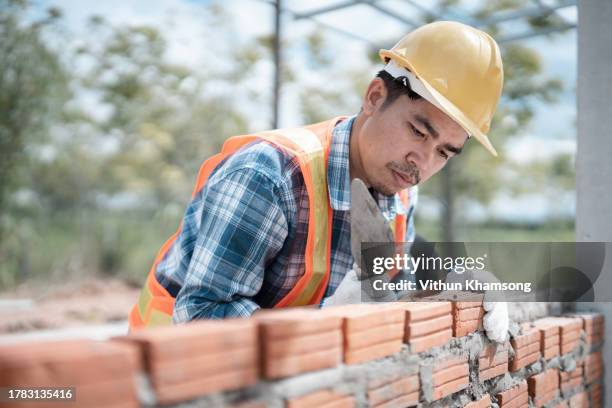 bricklayer worker installing bricks on construction site, exterior wall of building. - pedreiro imagens e fotografias de stock