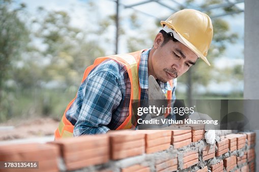 Bricklayer worker installing bricks on construction site, exterior wall of building. Bricklayer worker installing bricks on construction site, exterior wall of building.