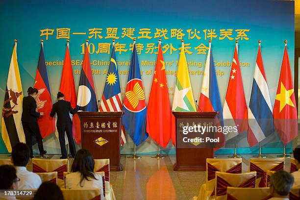 Personnel prepare flags before a press briefing for the first meeting of the opening session of the ASEAN Foreign Ministers meeting at the Diaoyutai...