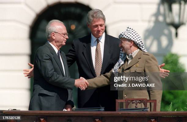 President Bill Clinton stands between PLO leader Yasser Arafat and Israeli Prime Minister Yitzahk Rabin as they shake hands for the first time, on...