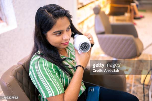 peluquera sentada en el salón sosteniendo su cabello con secador de pelo y cepillo de pelo redondo - hot indian model fotografías e imágenes de stock