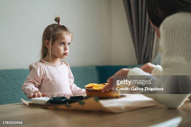 young mother scolds her offended daughter at table in the kitchen at home - kids arguing stock pictures, royalty-free photos & images