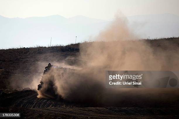 Israeli soldiers ride on top of their armored vehicle during a military exercise on August 29, 2013 near the border with Syria, in the...