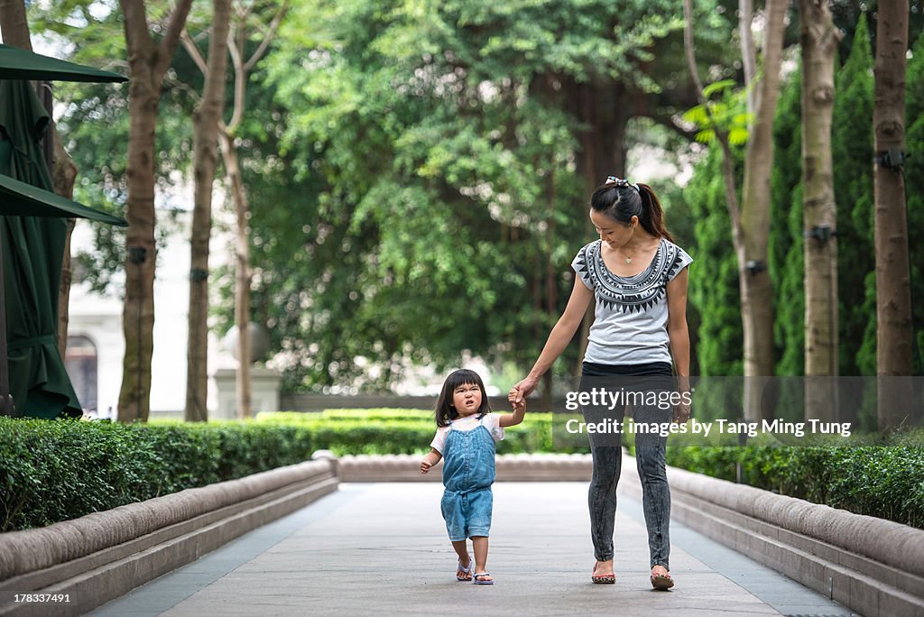 Young mom strolling in a pathway with toddler girl