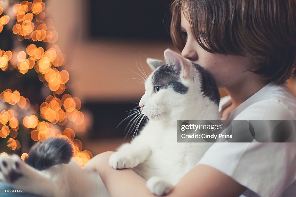 A boy holding his cat during Christmas