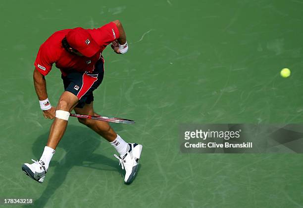 Carlos Berlocq of Argentina returns a shot through his legs during his men's singles second round match against Roger Federer of Switzerland on Day...