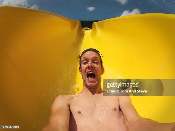 a man riding a yellow waterslide - water slide stock pictures, royalty-free photos & images