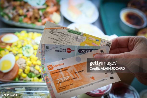 This photograph taken in Paris, on November 15, 2023 shows traditional meal vouchers by Edenred and UpDejeuner, called "Tickets restaurant", used by...