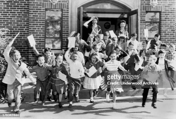 Second graders rush out the door on the last day of school while their teacher bids them goodbye, Mt. Carmel, Ohio, c. 1963.