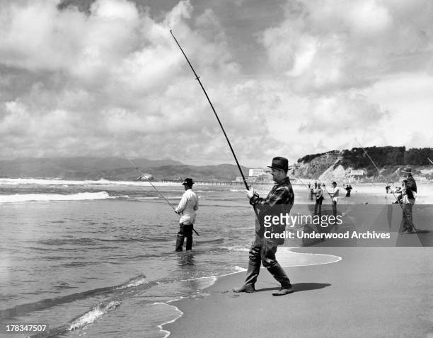 Men surf fishing at Ocean Beach in San Francisco. The Cliff House is visible in the background, San Francisco, California, c. 1940.