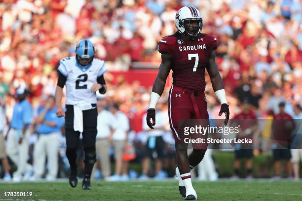 Jadeveon Clowney of the South Carolina Gamecocks watches on as Bryn Renner of the North Carolina Tar Heels follows behind during their game at...