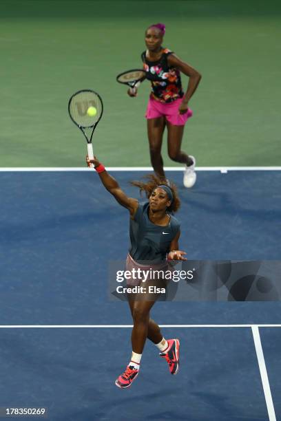 Serena Williams of the United States of America smashes the balll in front of her partner Venus Williams of the United States of America during their...