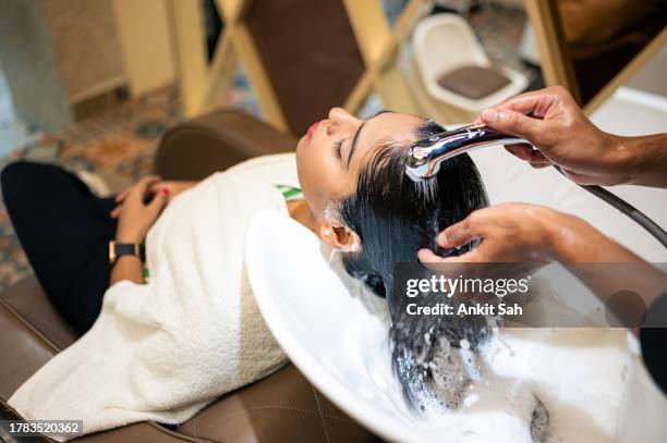 young woman enjoying while getting her hair washed by professional hairdresser at salon - salon wash basins stock pictures, royalty-free photos & images