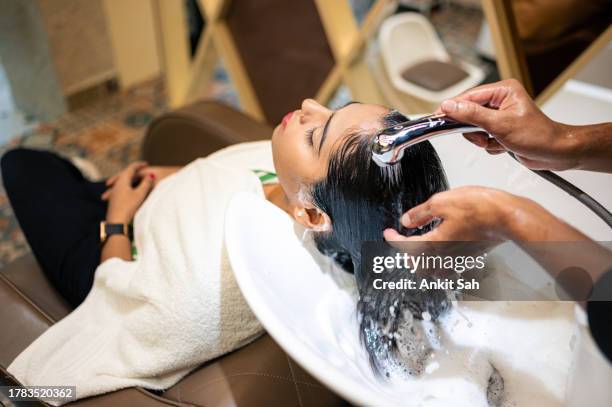 young woman enjoying while getting her hair washed by professional hairdresser at salon - hair color saloon stock pictures, royalty-free photos & images