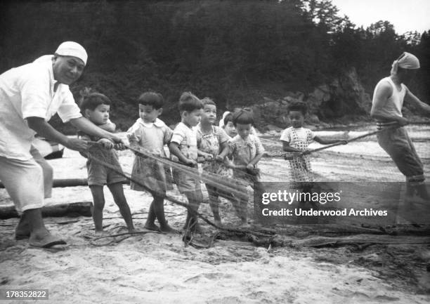 Children in a postwar orphanage learning to fish with nets, Japan, c. 1950.